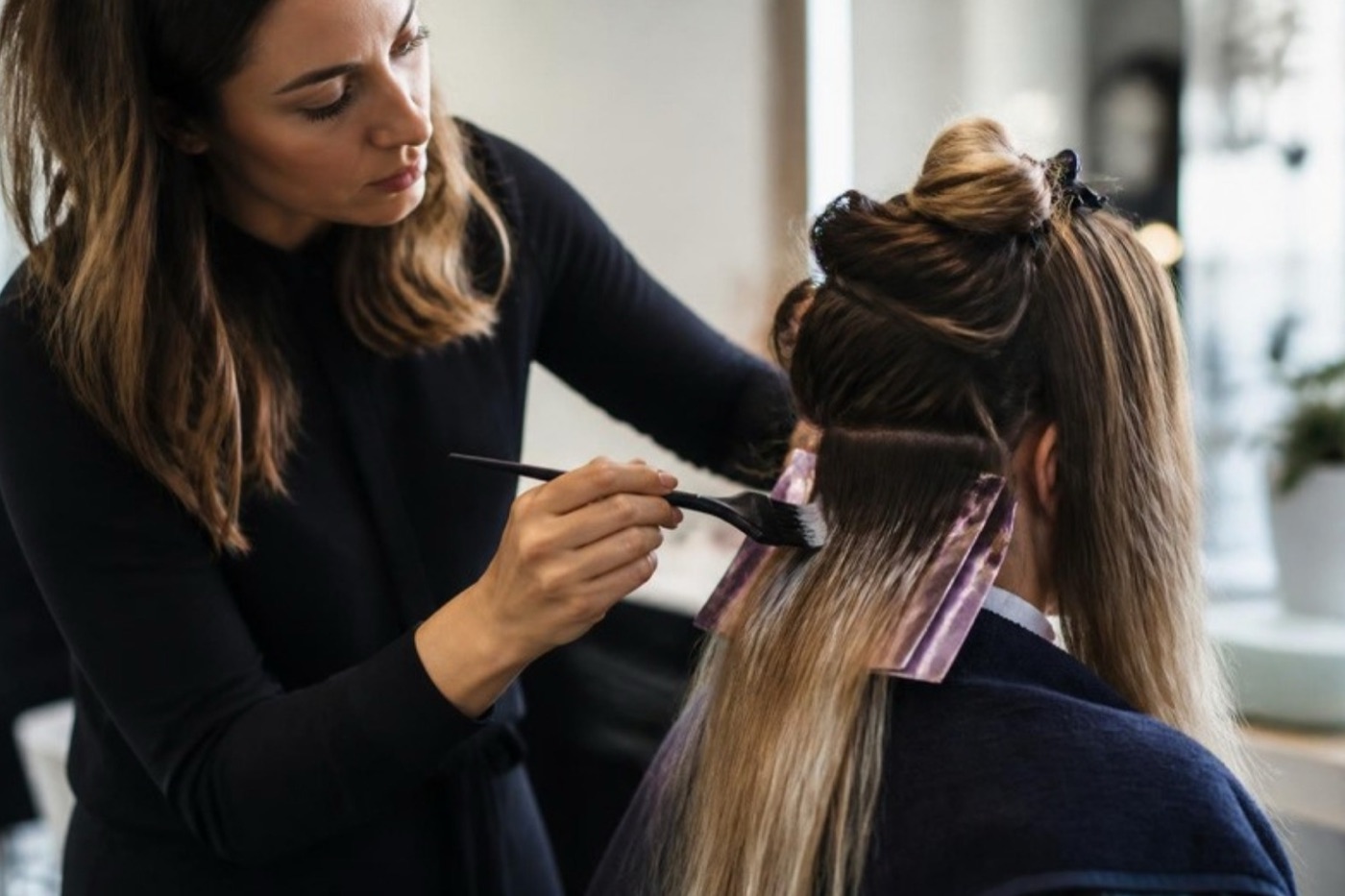 Coiffeuse trägt Balayage-Farbe mit dem Pinsel auf
