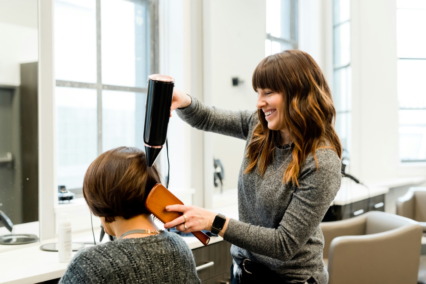 Coiffeuse föhnt einer Kundin die Haare