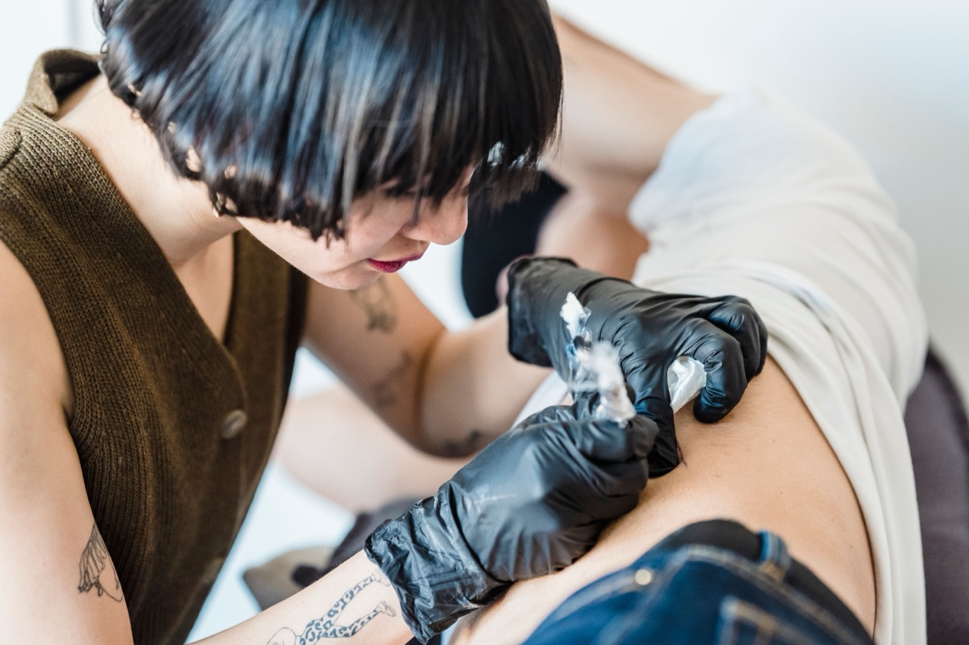 Tätowiererin mit Handschuhen bei der Arbeit